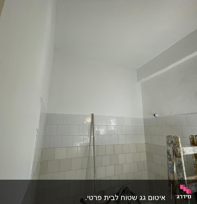 סולם ליד קיר עם אריחים לבנים ותקרה צבועה